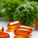 Capsule di olio di pesce Omega-3 su un tavolo con verdure a foglia verde, simbolo di salute cerebrale e infiammazione.