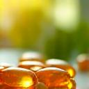 Pillole di vitamina D illuminate dal sole in un cucchiaio, simbolo di salute ossea e immunità.